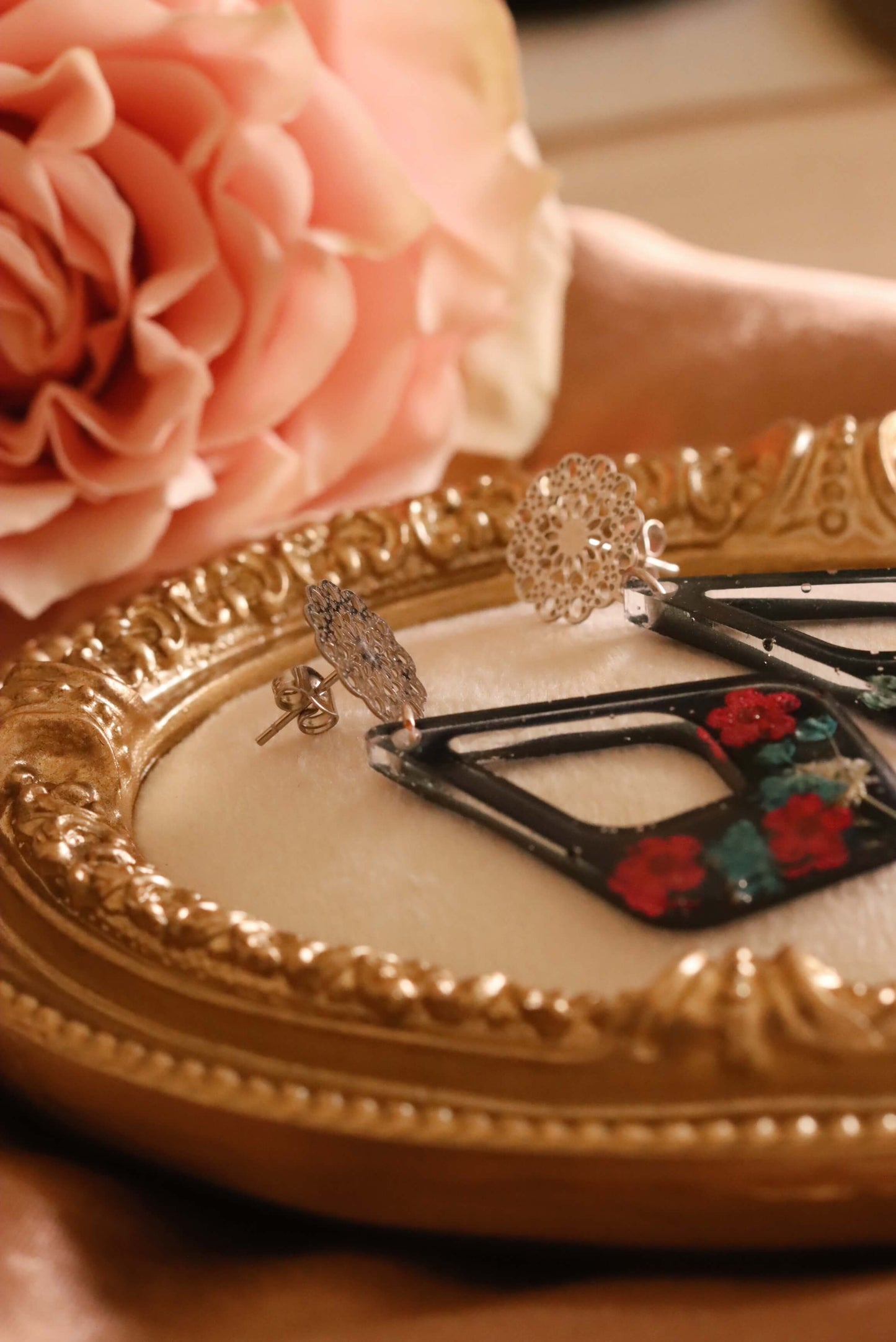 Side-view of the Floral Romance Resin Earrings - part of the Gothic Romance Jewelry Collection by Kaleidoscopes And Polka Dots. These earrings feature a midnight blue background and are displayed on a beige jewelry tray with gold trim.