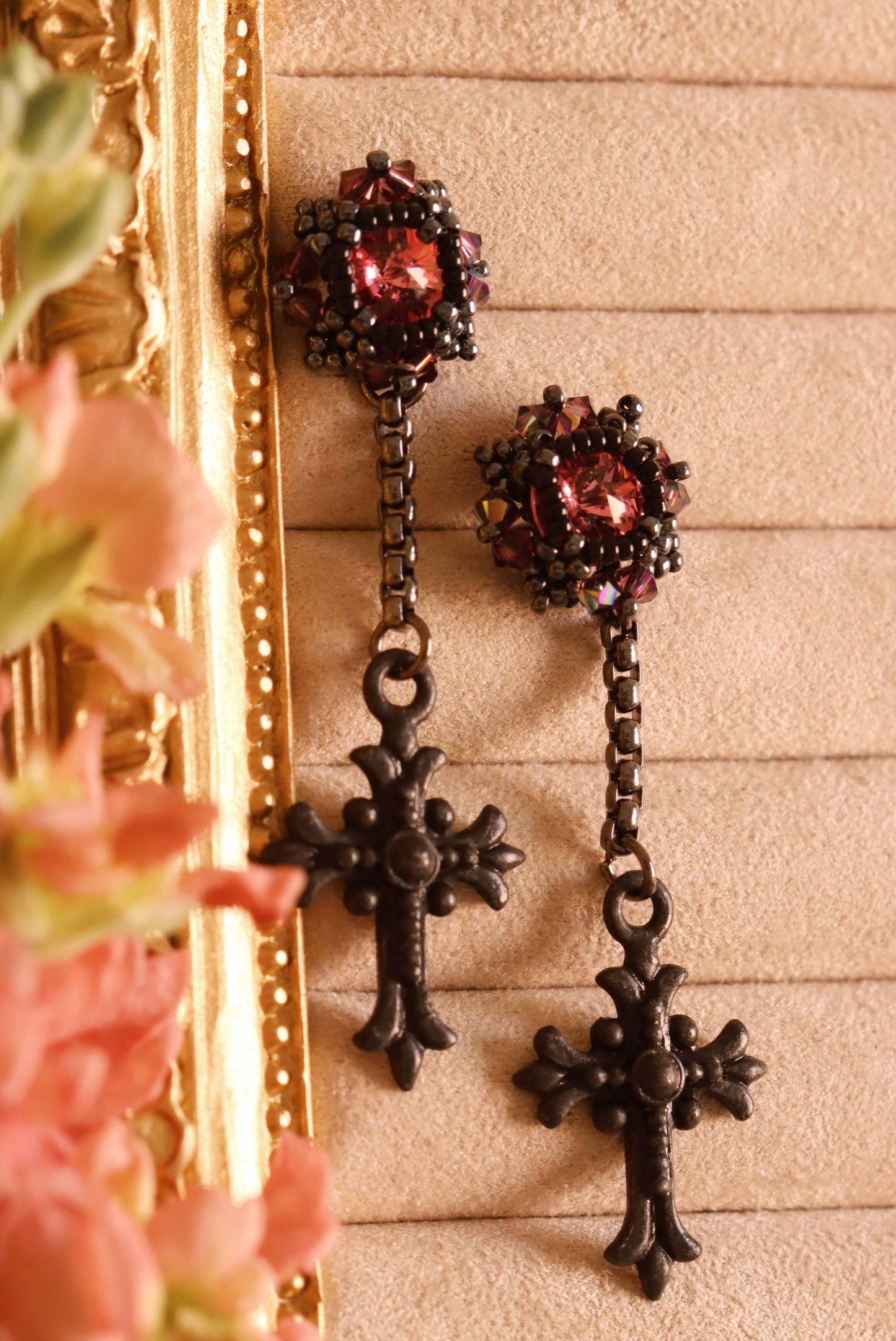 Beaded drop gothic earrings with pink crystals and black crosses on a textured beige background.