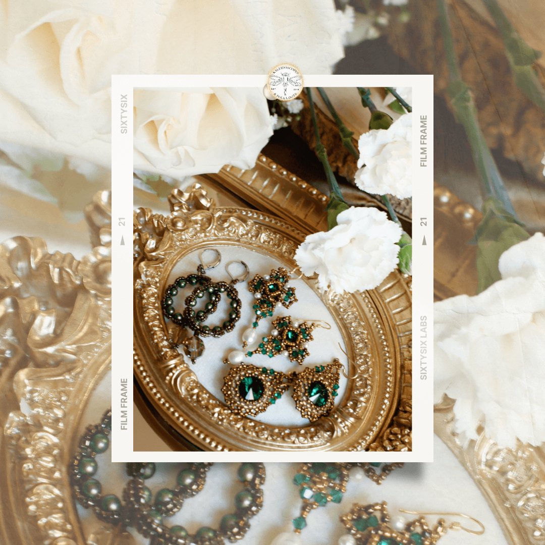 Gold jewelry with green crystals on a decorative plate surrounded by white flowers.