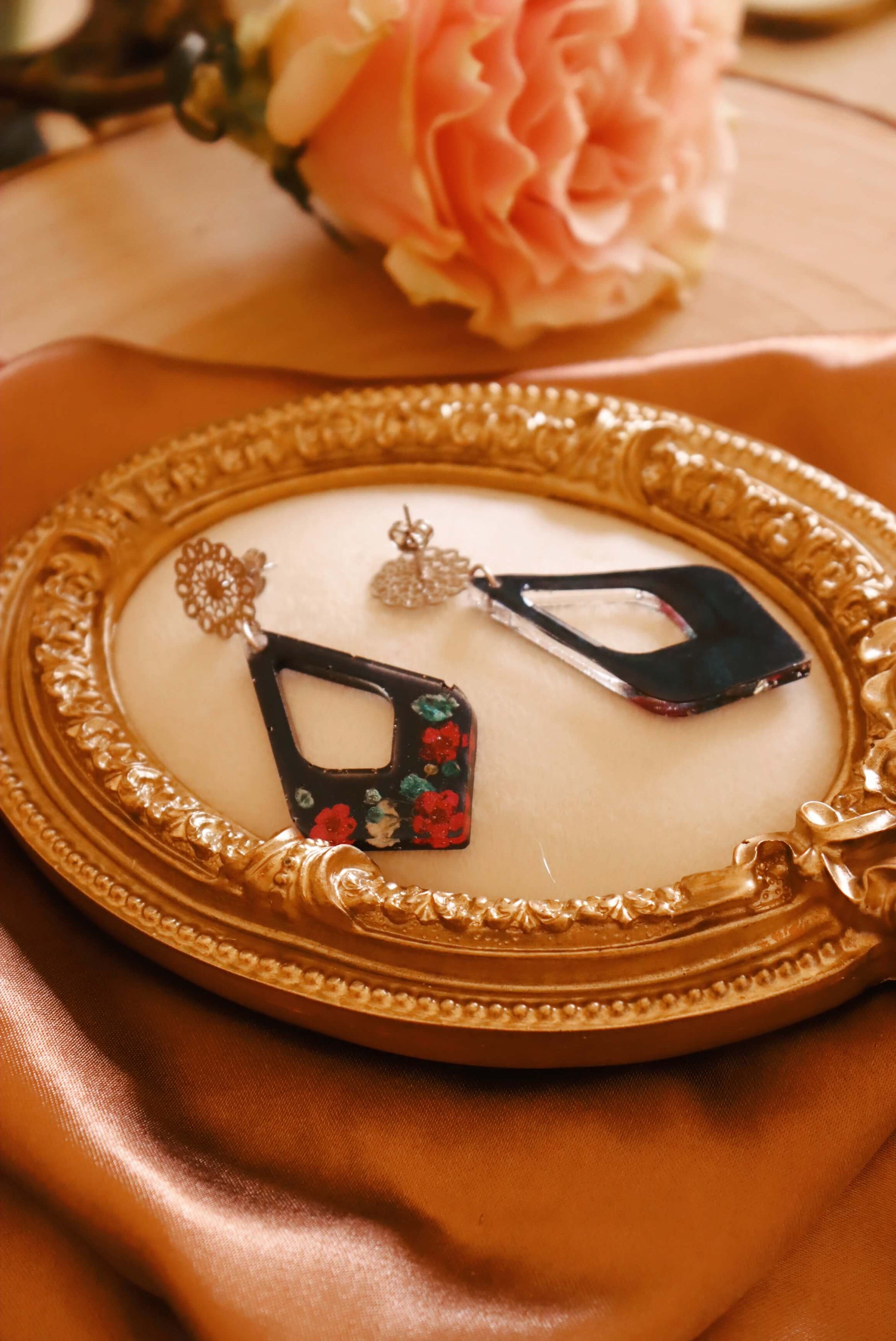 Font and back view of the Floral Romance Resin Earrings - part of the Gothic Romance Jewelry Collection by Kaleidoscopes And Polka Dots. These earrings feature a midnight blue background and are displayed on a beige jewelry tray with gold trim. 